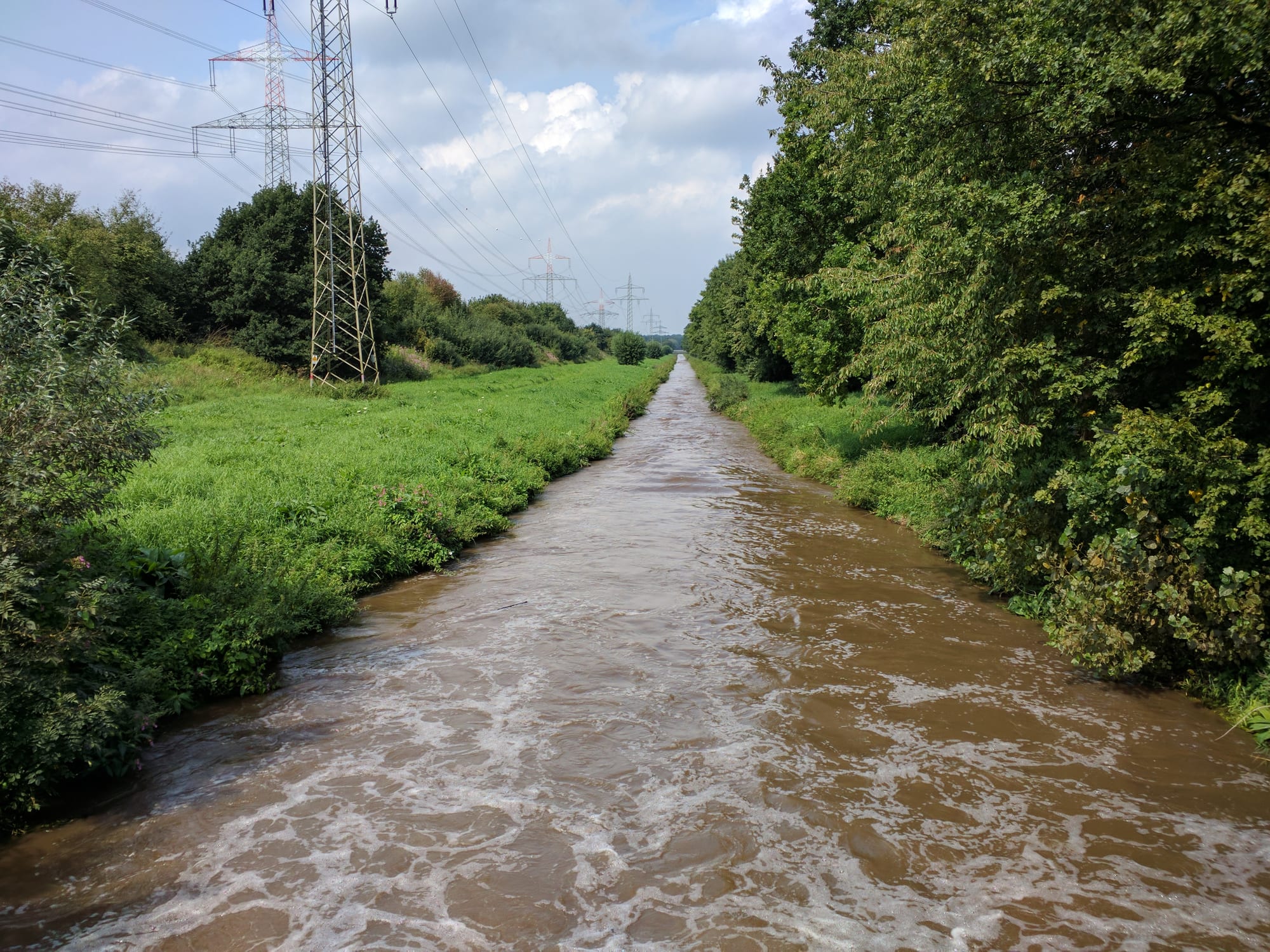 River and open sky in the Gymnich landscape with green vegetation and electrical towers